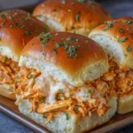 Tray of golden baked buffalo chicken sliders topped with garlic butter