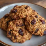 A hand holding a soft, chewy cookie with visible oats and chocolate chips.