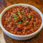 Overhead shot of chili simmering in a pot with steam rising.